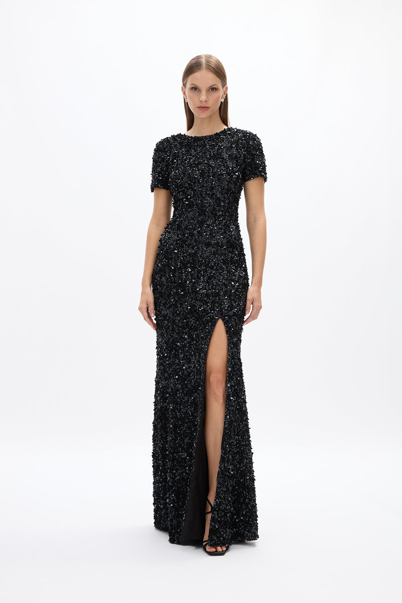 Nixie Gown: elegant floor-grazing black gown featuring hand-embellished details, cap sleeves, and high front split, perfect for evening events. 